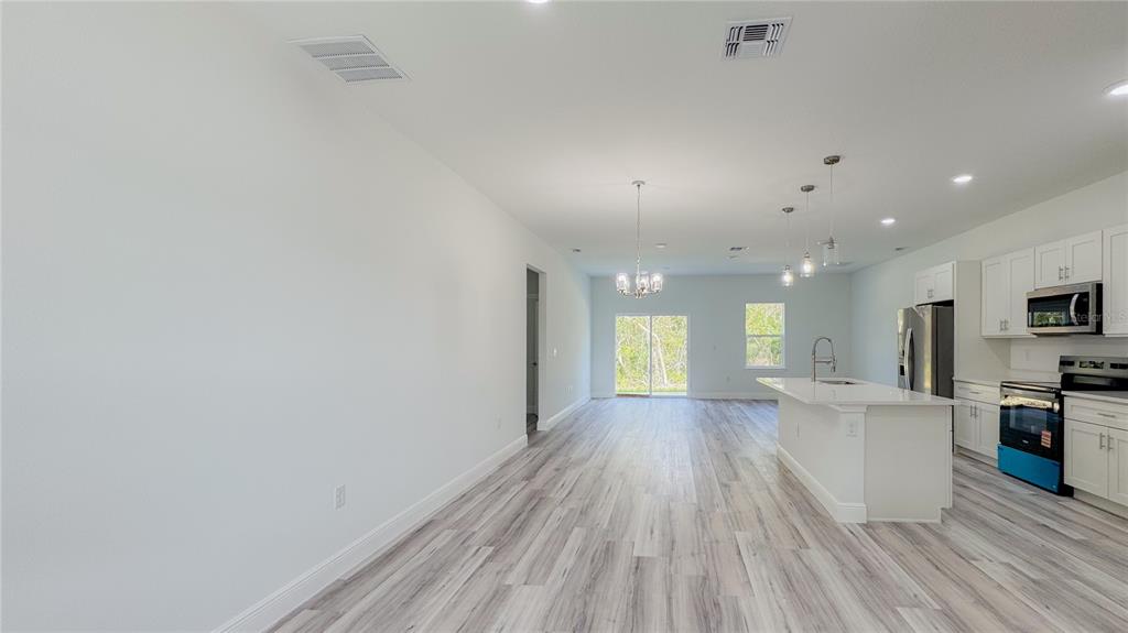 An open-concept kitchen and living area featuring white cabinets, a center island, and wood flooring — 15625 SW 37TH CIRCLE, OCALA, FL