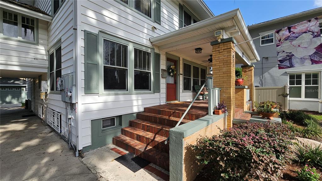 A white house with green shutters features a brick porch and steps leading to a door — 821 N EOLA DRIVE, ORLANDO, FL