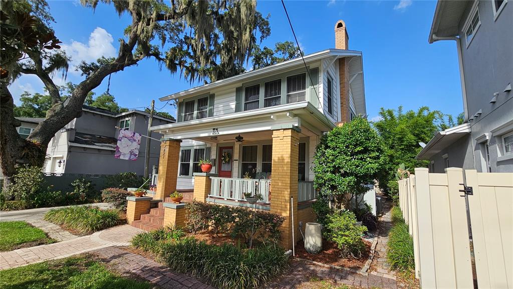 A two-story white house with green shutters features a front porch and a side driveway — 821 N EOLA DRIVE, ORLANDO, FL