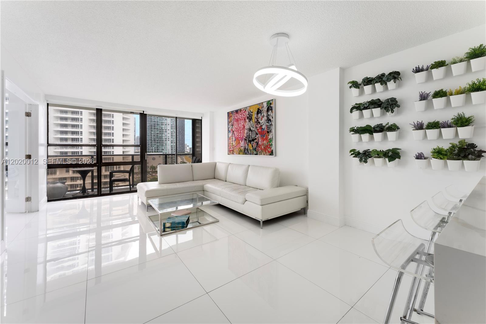 A modern living room features white tile floors, a white sectional sofa, and wall-mounted planters — 600 NE 36th St # 1111, Miami FL 33137, MIAMI, FL