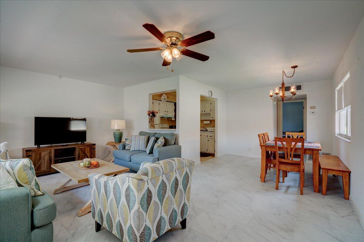 A living and dining area with white tile floors, a ceiling fan, and wooden furniture — 222 Saxony E # 222, Delray Beach FL 33446, DELRAY BEACH, FL
