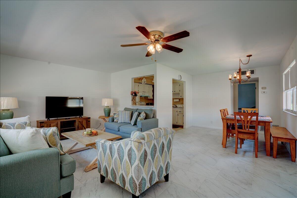 An open-concept living and dining area with white walls, tile flooring, and a ceiling fan — 222 Saxony E # 222, Delray Beach FL 33446, DELRAY BEACH, FL