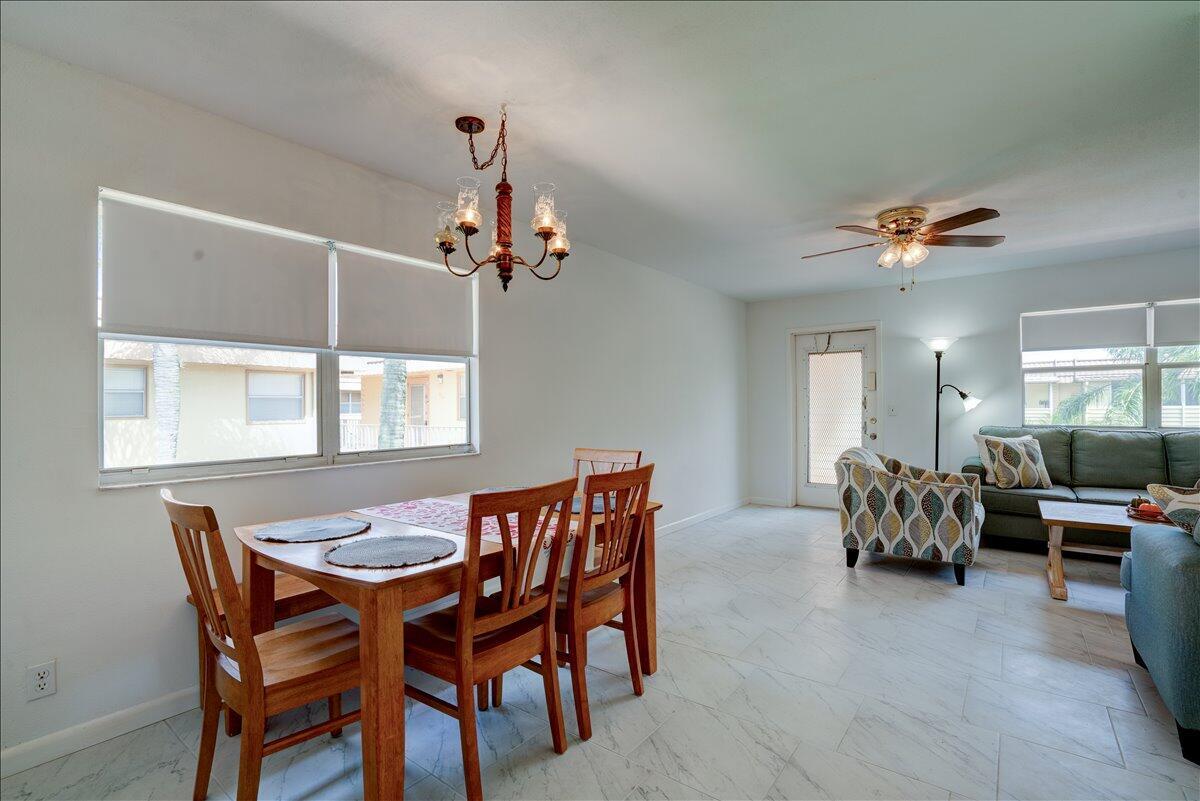 An open-concept dining and living area with tile flooring, a chandelier, and a ceiling fan — 222 Saxony E # 222, Delray Beach FL 33446, DELRAY BEACH, FL
