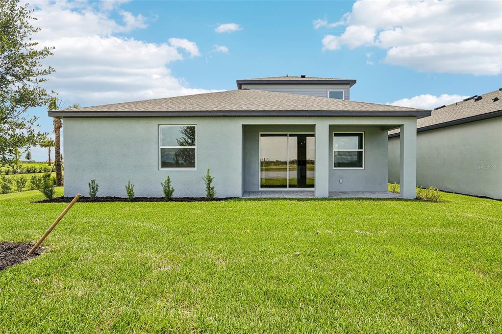The exterior rear view of a single-story house features a covered patio and lawn — 8724 CANARD COVE, PALMETTO, FL