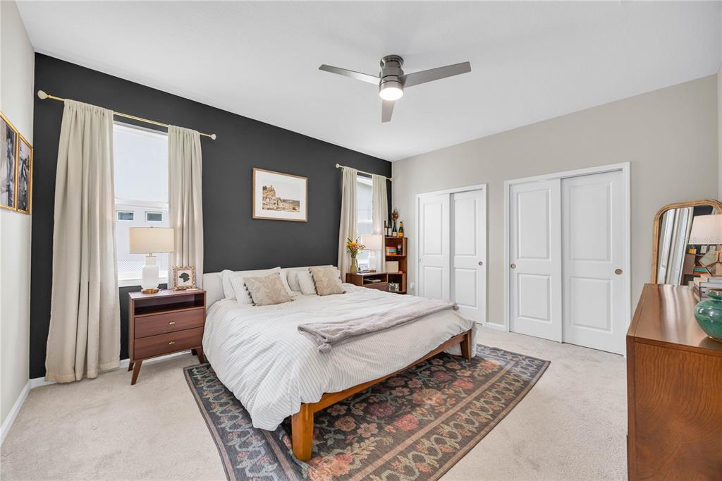 A bedroom features a dark accent wall, a bed with a patterned rug, and two closets — 4316 RENLY LANE, CLERMONT, FL