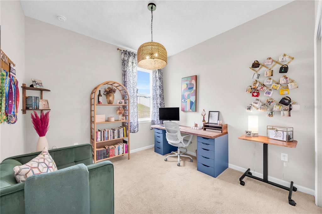 A home office features a desk, a bookshelf, a green armchair, and a wall-mounted mug rack — 4316 RENLY LANE, CLERMONT, FL