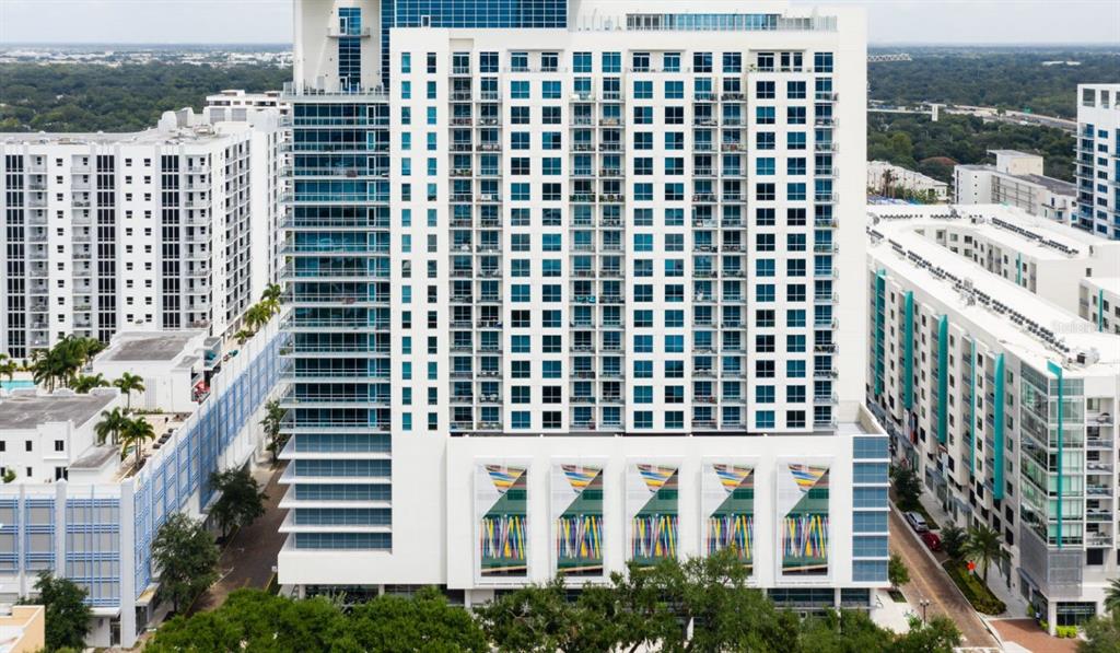 An aerial view of a tall, modern white apartment building with blue glass balconies and windows — 101-1 LAKE AVENUE, ORLANDO, FL
