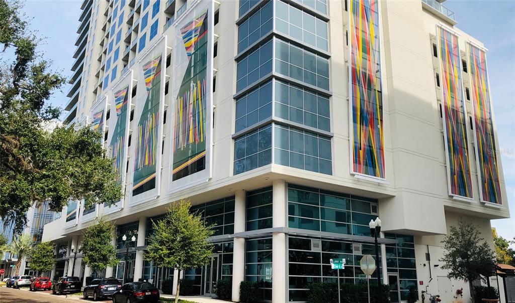 A multi-story building features glass windows and large, colorful vertical art panels on its exterior — 101-1 LAKE AVENUE, ORLANDO, FL
