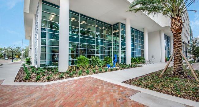 A modern building exterior features a glass facade, white columns, and a brick walkway — 101-1 LAKE AVENUE, ORLANDO, FL