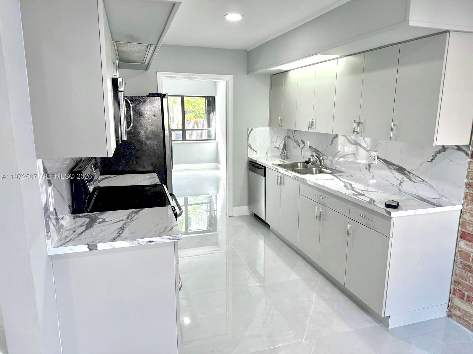 A modern kitchen features white cabinets, marble-patterned countertops, and a matching backsplash — 2700 N 34th Ave # I, Hollywood FL 33021, HOLLYWOOD, FL