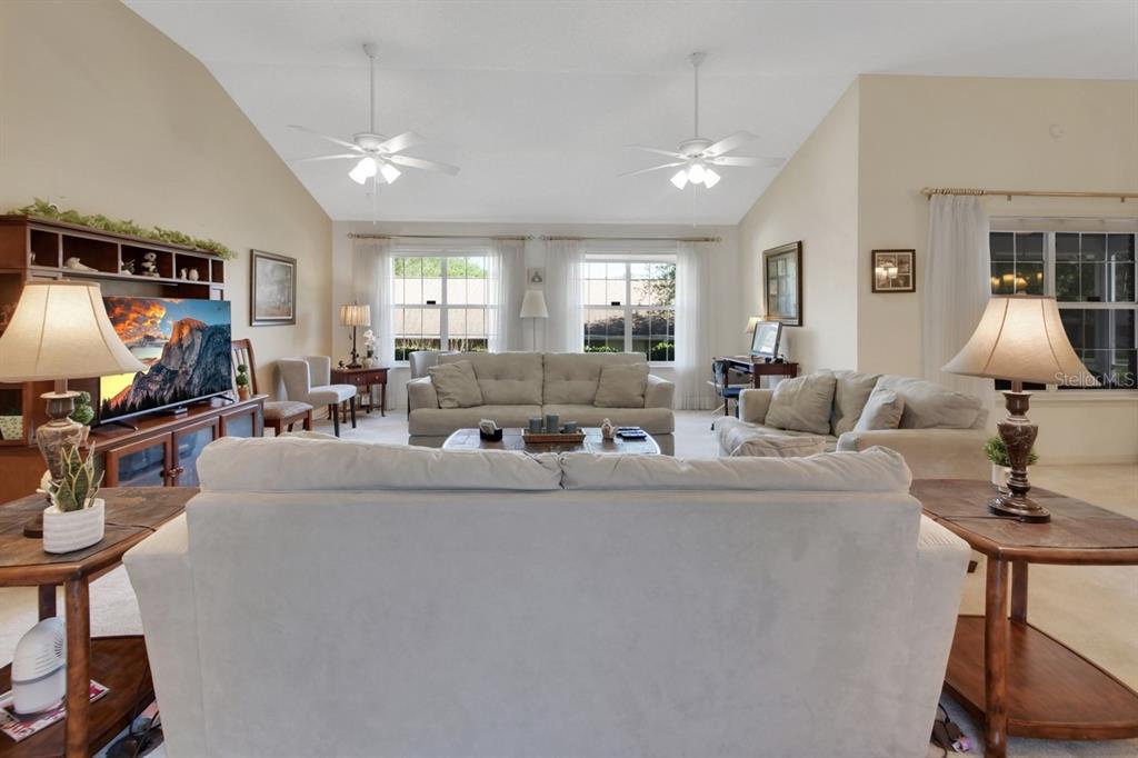 A spacious living room features vaulted ceilings, two ceiling fans, and neutral-toned furniture — 2520 S GLEN EAGLES DRIVE, DELAND, FL