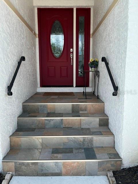 A set of tiled stairs with black handrails leads to a red front door — 4716 61ST AVENUE TERRACE W UNIT 4716, BRADENTON, FL