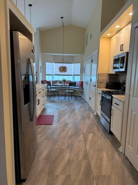 A kitchen with stainless steel appliances and wood-look flooring leads to a dining nook — 4716 61ST AVENUE TERRACE W UNIT 4716, BRADENTON, FL