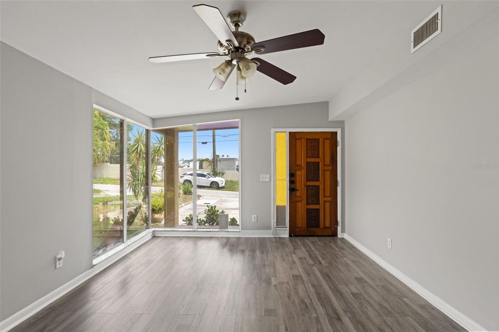A room with gray wood-look flooring, a ceiling fan, large windows, and a wooden door — 2116 W ABDELLA STREET, TAMPA, FL