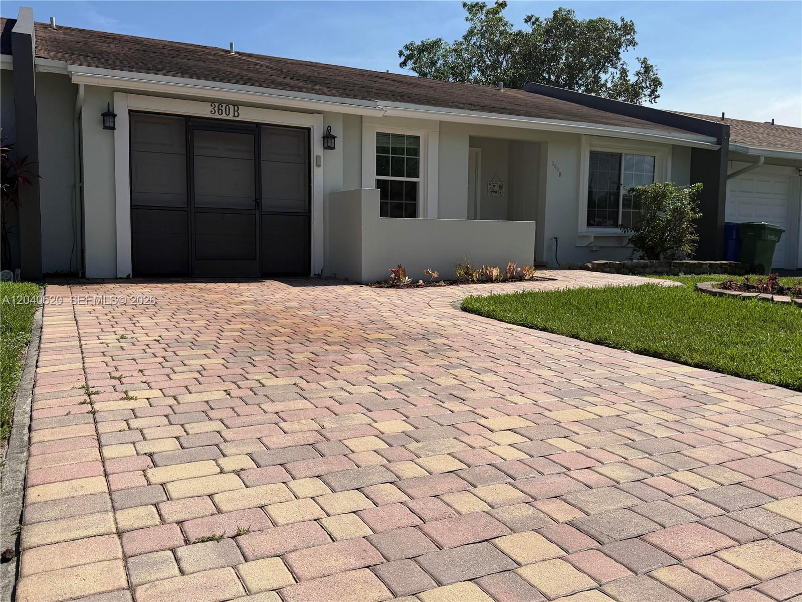 A single-story house features a paved driveway, a screened entryway, and a small front lawn — 360 B Lakewood Cir E, Margate FL 33063, MARGATE, FL