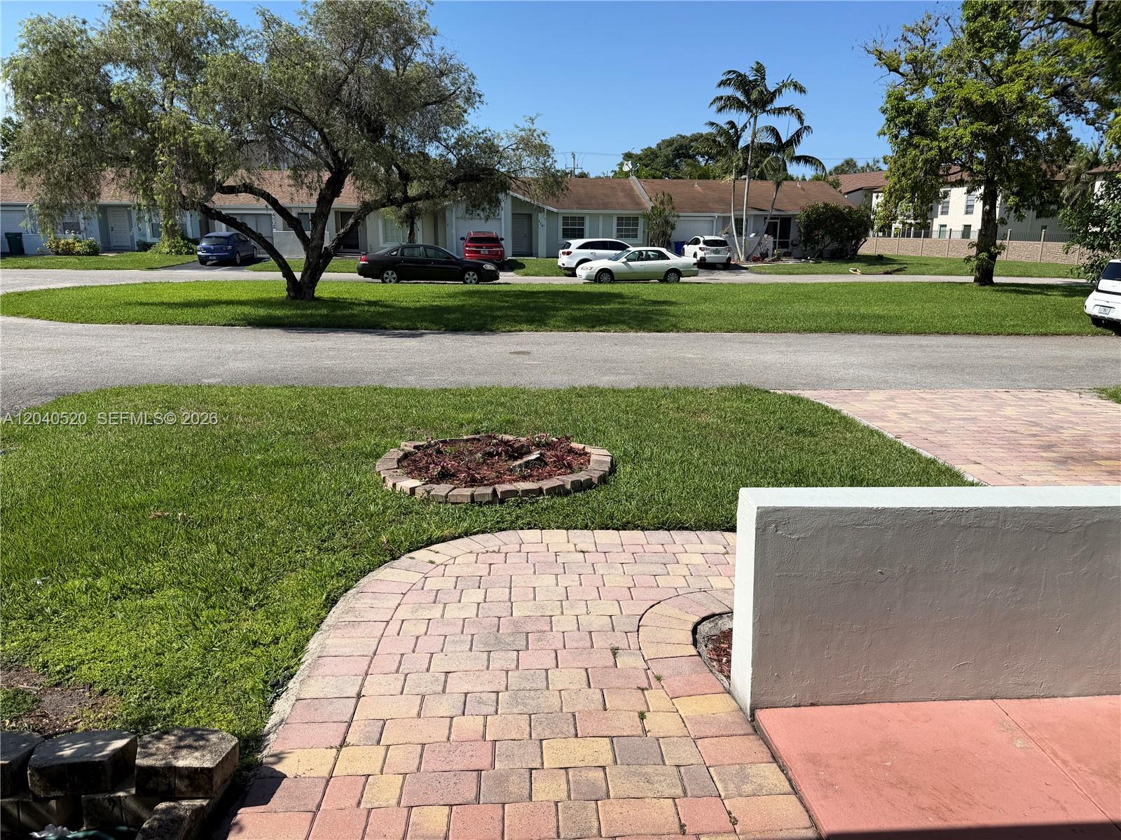 A paved walkway leads toward a lawn with a circular planter and residential buildings beyond — 360 B Lakewood Cir E, Margate FL 33063, MARGATE, FL