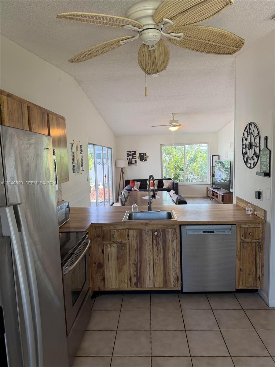 A kitchen with wood cabinets and stainless steel appliances overlooks a dining and living area — 360 B Lakewood Cir E, Margate FL 33063, MARGATE, FL