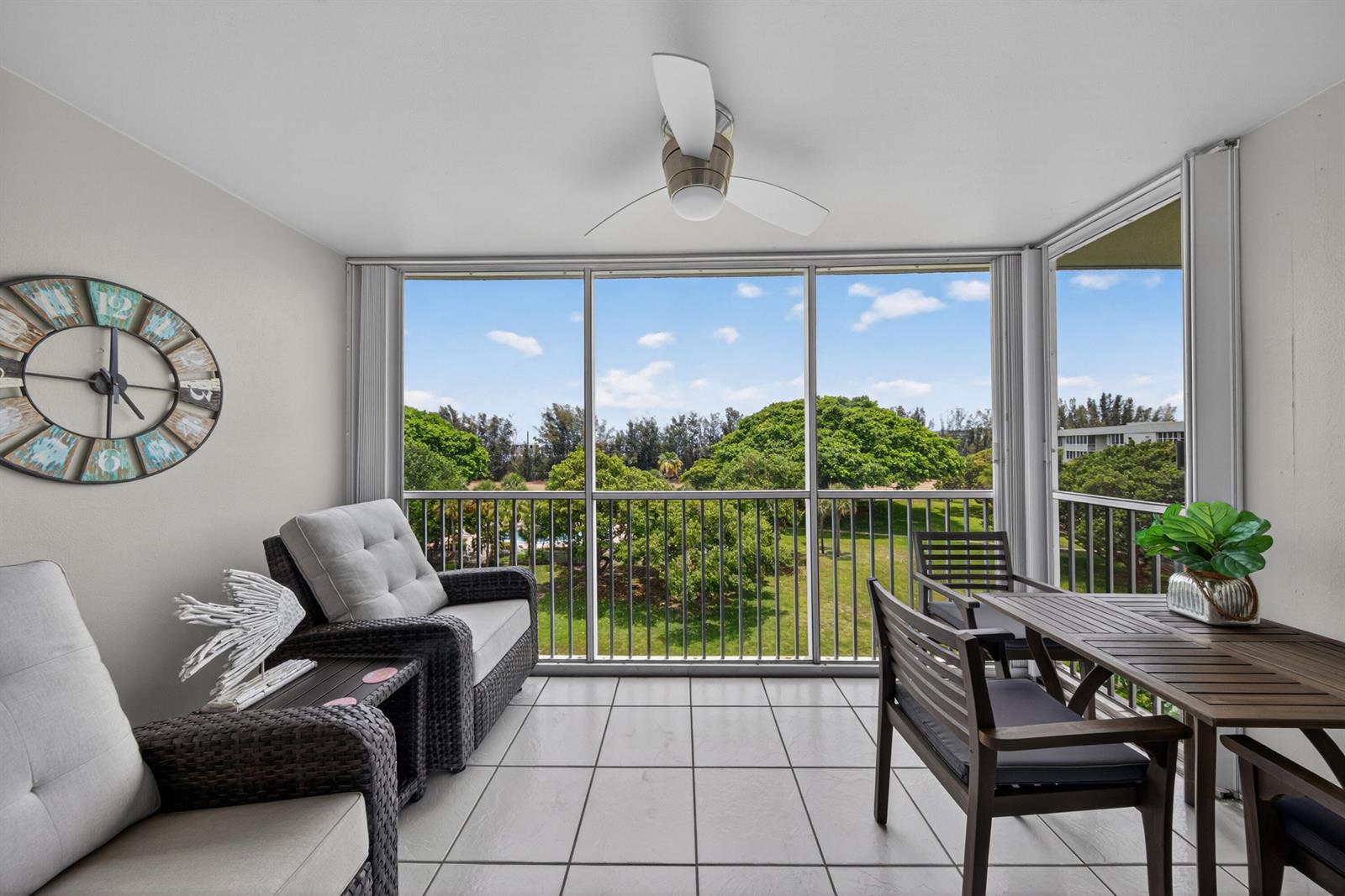 A screened-in balcony features tile flooring, wicker seating, a dining set, and a ceiling fan — 2650 S Course Drive # 603, Pompano Beach FL 33069, POMPANO BEACH, FL