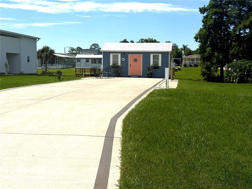A blue shed with a peach door sits at the end of a concrete driveway — 5147 ISLAND VIEW CIRCLE S, POLK CITY, FL