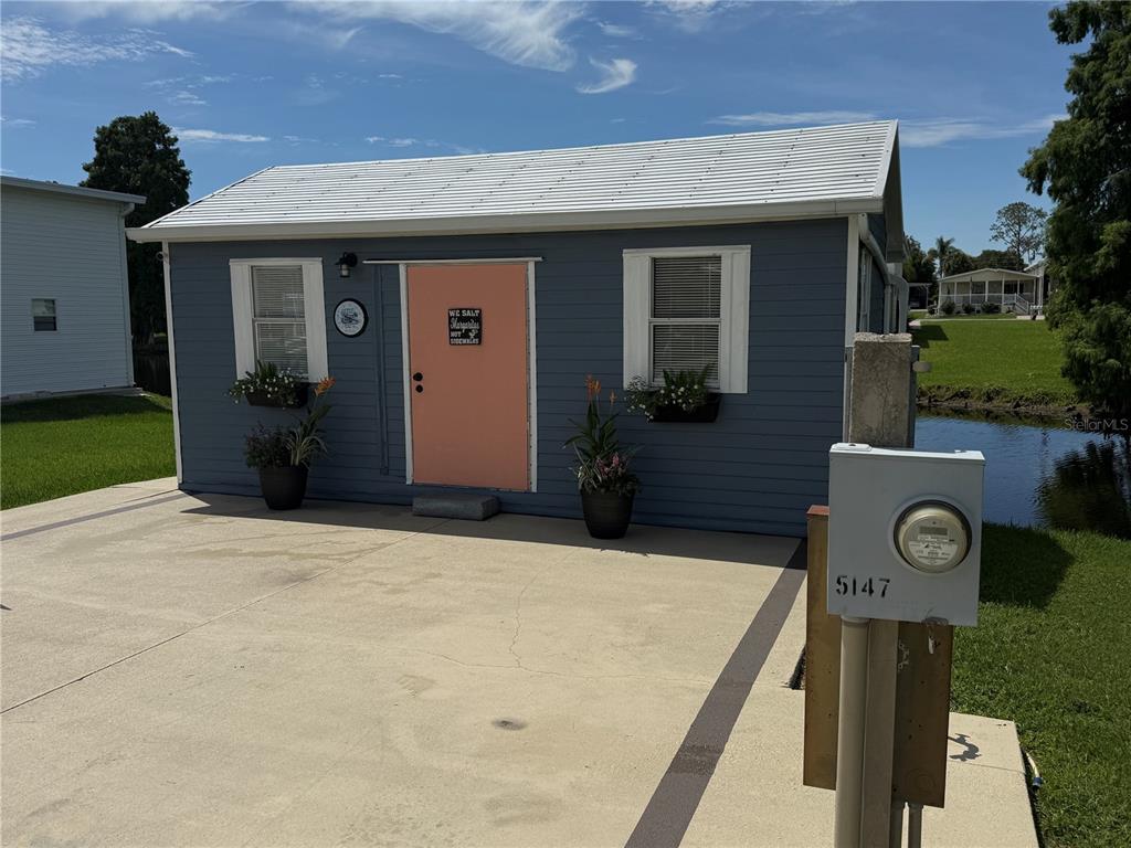 A small blue house with a coral door and a white metal roof — 5147 ISLAND VIEW CIRCLE S, POLK CITY, FL