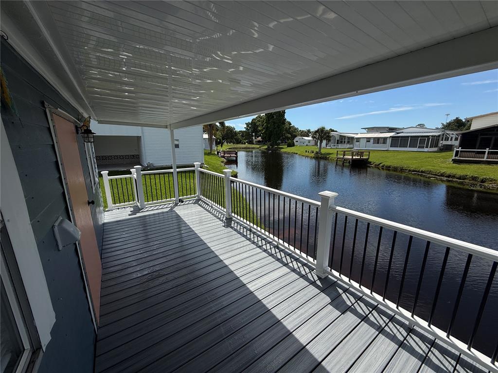 A covered deck with gray composite flooring overlooks a canal and neighboring homes — 5147 ISLAND VIEW CIRCLE S, POLK CITY, FL