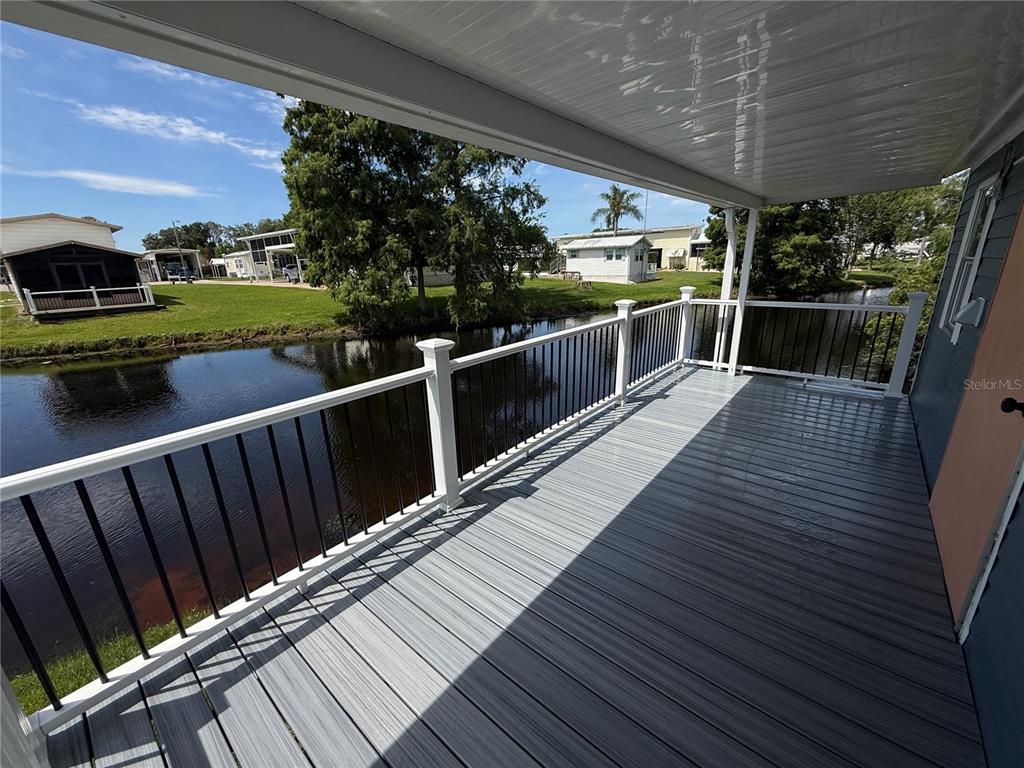 A covered deck with gray composite flooring overlooks a canal and neighboring homes — 5147 ISLAND VIEW CIRCLE S, POLK CITY, FL