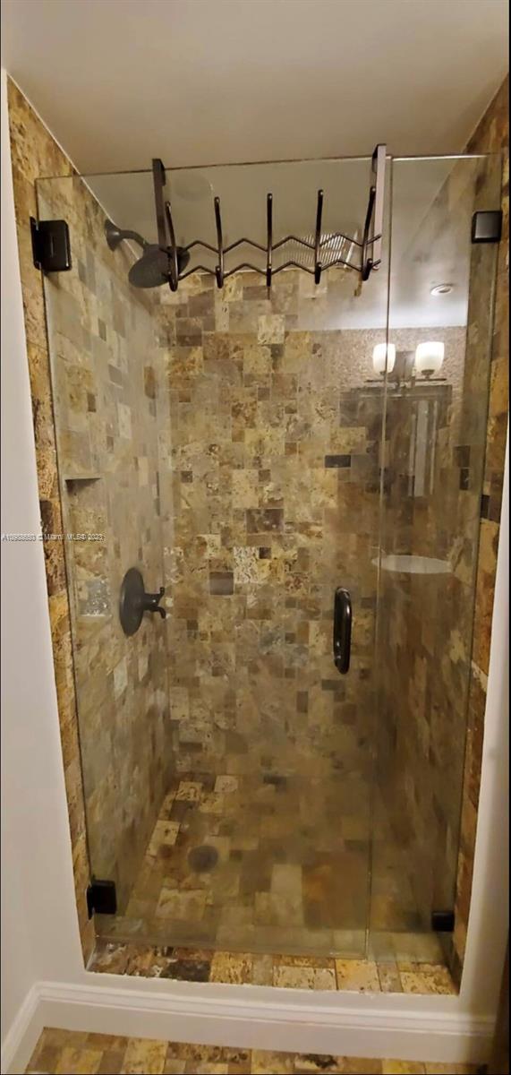 A walk-in shower features a glass door, dark hardware, and brown stone tile walls — 753 Michigan # 2B, Miami Beach FL 33139, MIAMI BEACH, FL