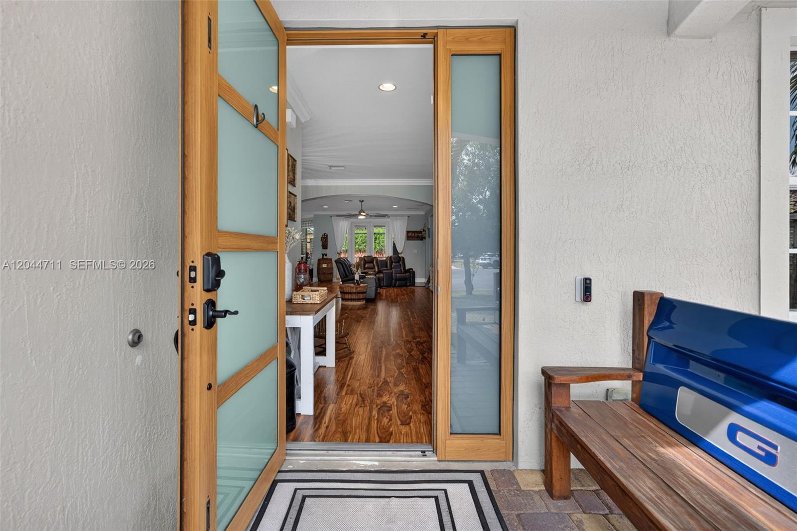 An open front door reveals a living room with hardwood floors and a wooden bench — 2135 NW 14th Ter, Homestead FL 33030, HOMESTEAD, FL