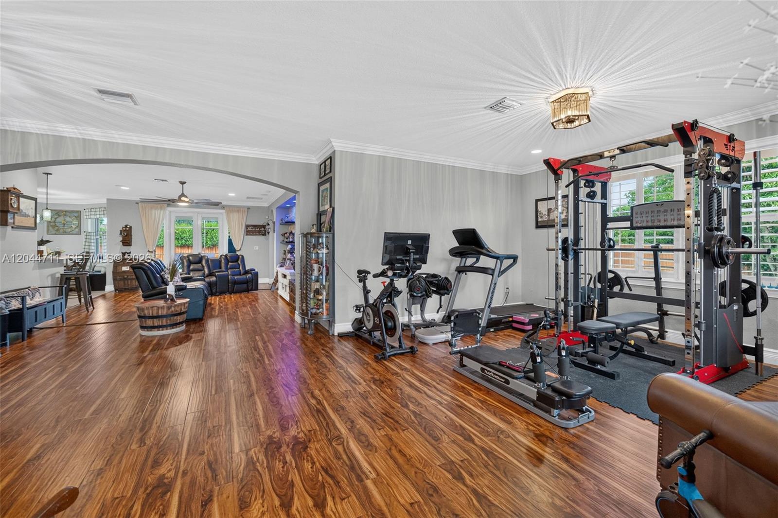 A home gym area with exercise equipment transitions into a living room with wood flooring — 2135 NW 14th Ter, Homestead FL 33030, HOMESTEAD, FL