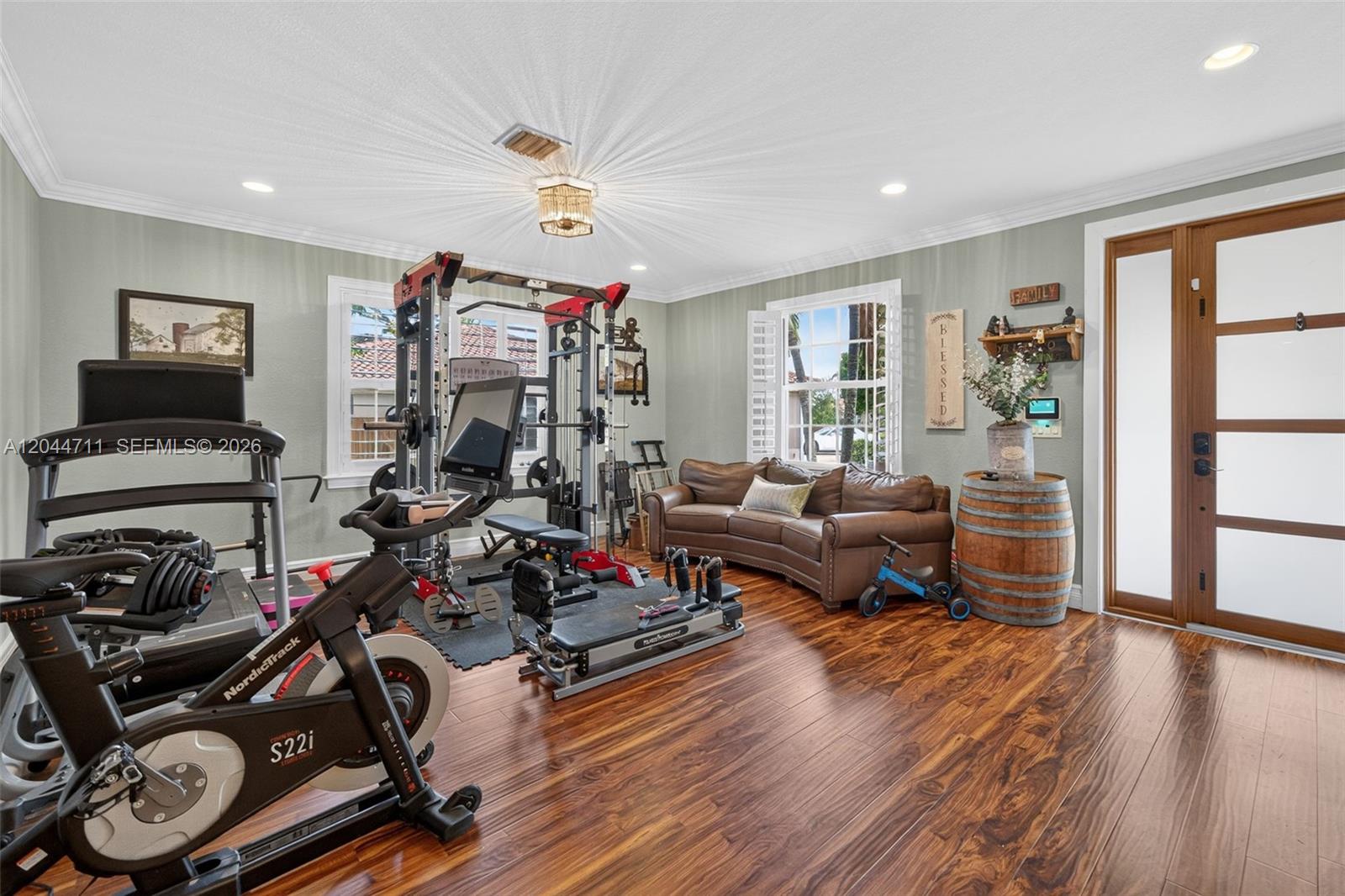 A home gym features exercise equipment, a brown leather sofa, and wood flooring — 2135 NW 14th Ter, Homestead FL 33030, HOMESTEAD, FL