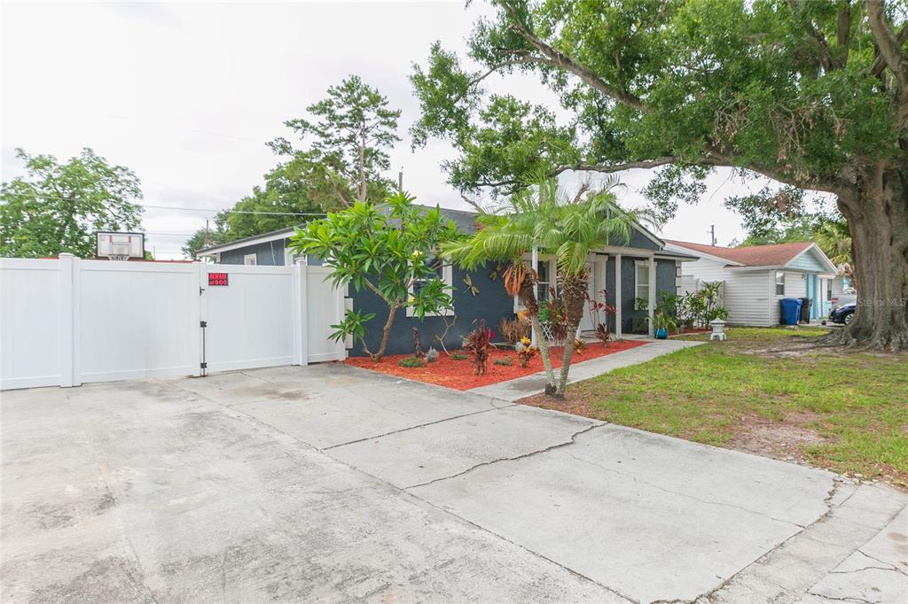 A single-story house with a dark blue exterior, a concrete driveway, and a white fence — 7412 KINGSTON DRIVE, TAMPA, FL