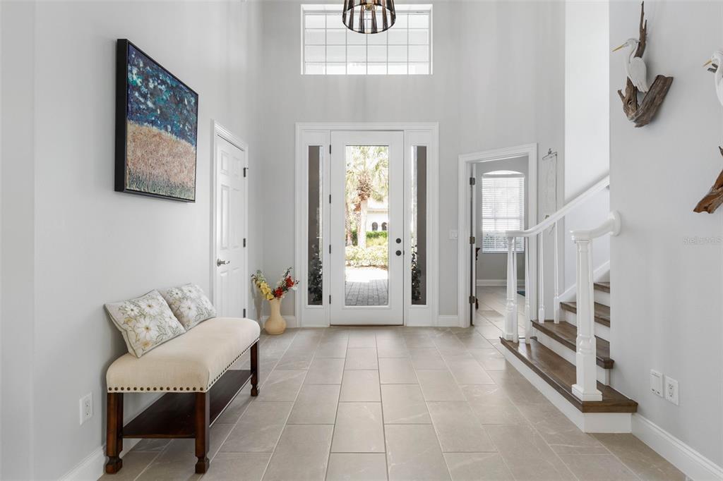 A bright foyer features tile flooring, a staircase with wood treads, and a glass-paneled front door — 34 SANDPIPER LANE, PALM COAST, FL