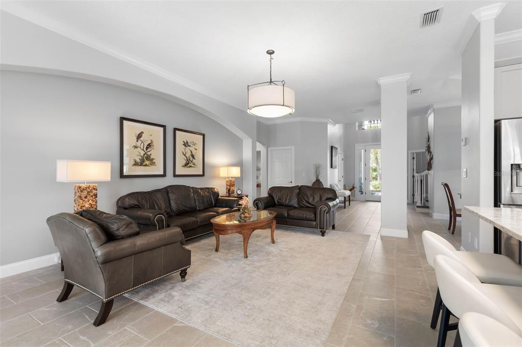 A living room features dark leather furniture, a neutral area rug, and tile flooring — 34 SANDPIPER LANE, PALM COAST, FL