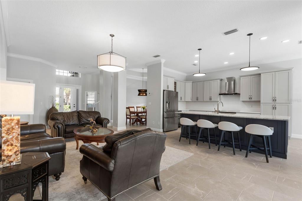 An open-concept living room and kitchen featuring dark leather furniture, a large island, and tile flooring — 34 SANDPIPER LANE, PALM COAST, FL
