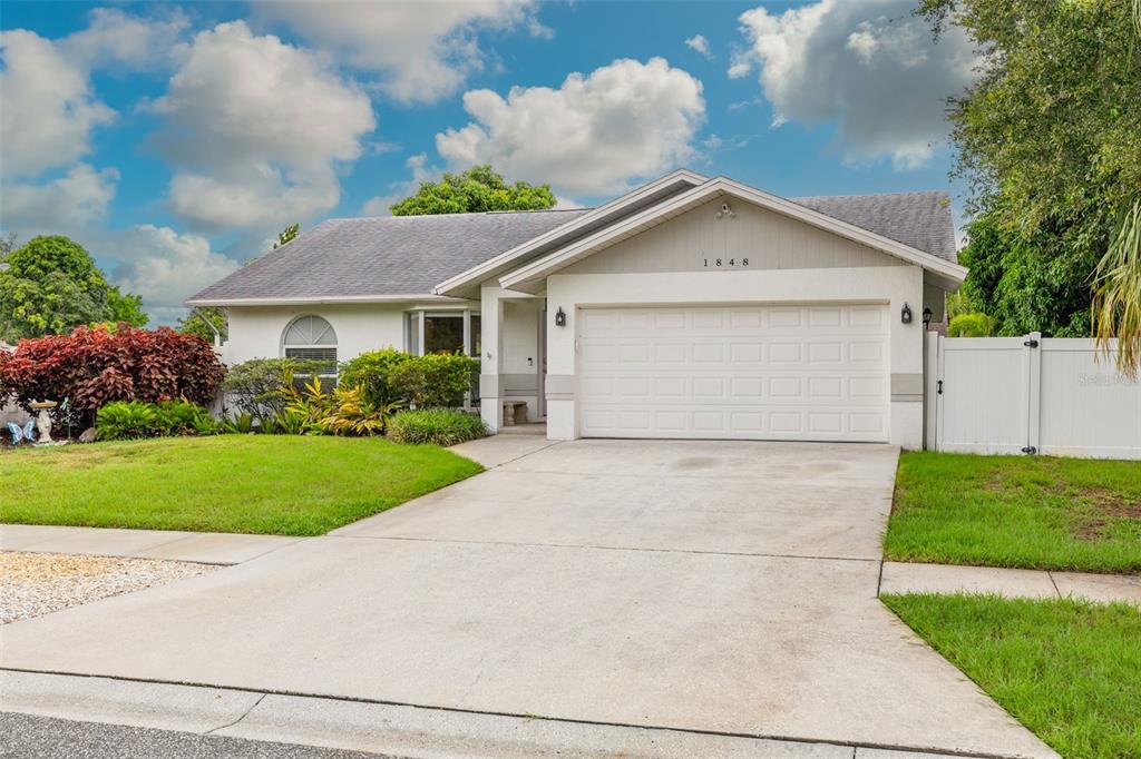 A living room with gray wood-look flooring, two dark gray sofas, and a white media console — 1848 77TH AVENUE N, ST PETERSBURG, FL