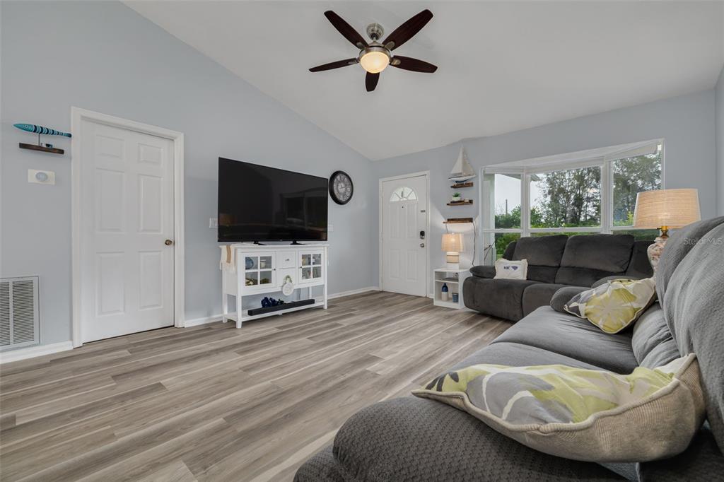 A kitchen features gray cabinets, white countertops, a center island with bar stools, and flooring — 1848 77TH AVENUE N, ST PETERSBURG, FL