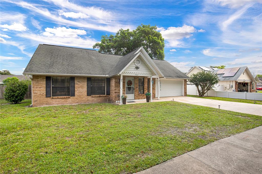 A single-story brick house with a gabled entryway, attached garage, and a front lawn — 7261 ABBEY LANE, WINTER PARK, FL