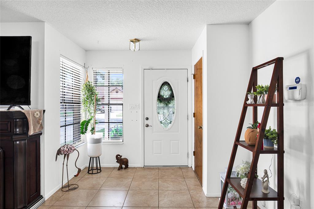 An entryway with tile flooring, a white front door, and a wooden ladder shelf — 7261 ABBEY LANE, WINTER PARK, FL