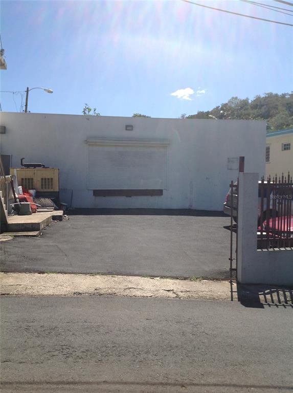 A white commercial building with a roll-up door and a paved parking lot in front — PR-837 KM 3.2 SANTA ROSA WARD, SECTOR EL LLANO UNIT A69 & A68, GUAYNABO, PR