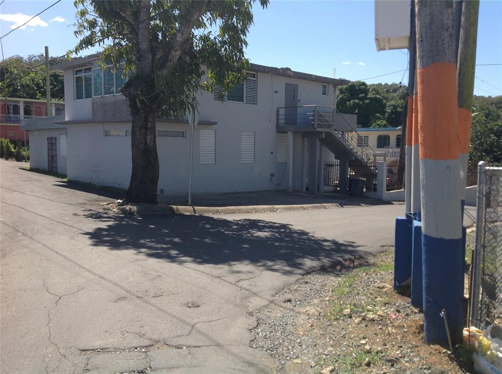 A two-story concrete building with an exterior staircase stands on a corner lot — PR-837 KM 3.2 SANTA ROSA WARD, SECTOR EL LLANO UNIT A69 & A68, GUAYNABO, PR