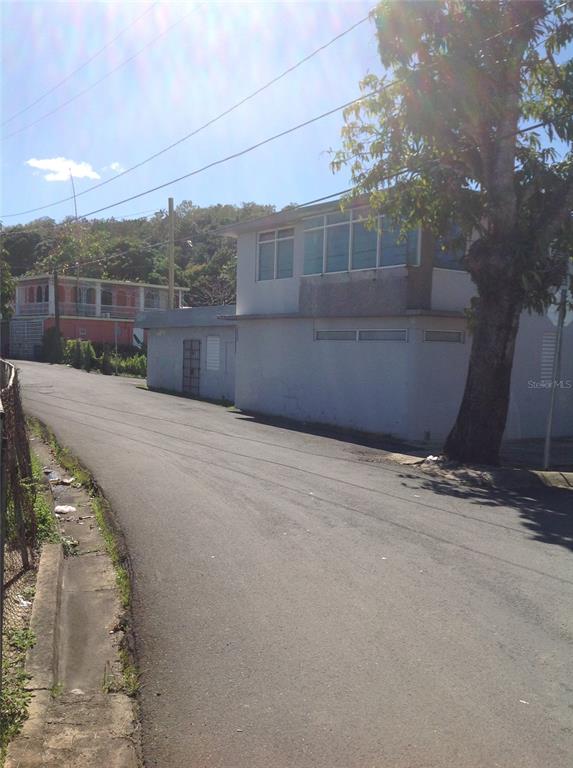 A two-story white building stands beside a paved road with a large tree in front — PR-837 KM 3.2 SANTA ROSA WARD, SECTOR EL LLANO UNIT A69 & A68, GUAYNABO, PR