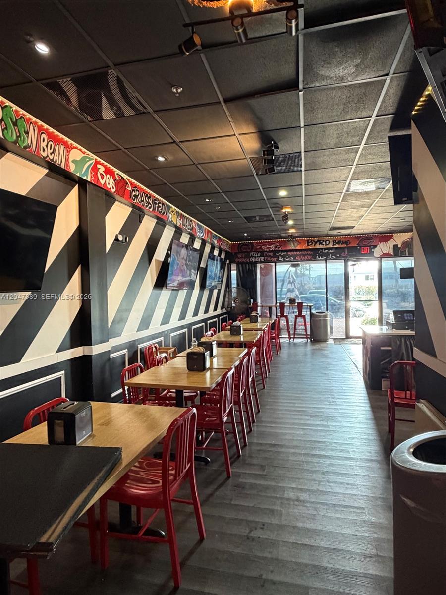 A restaurant interior features black and white striped walls, wooden tables, and red metal chairs — 1313 W Boynton Beach Blvd, Boynton Beach FL 33426, BOYNTON BEACH, FL