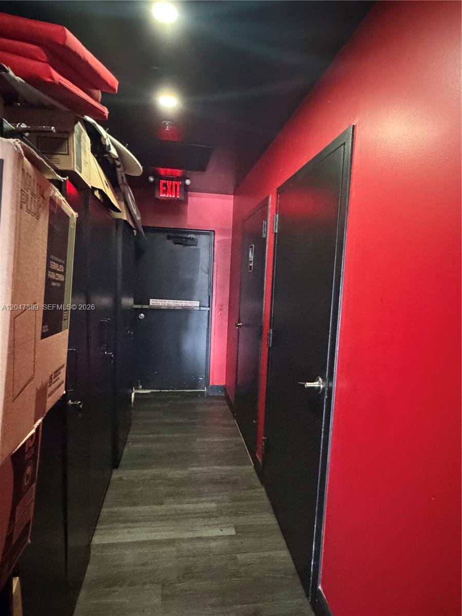 A narrow hallway features red walls, black doors, and an illuminated exit sign — 1313 W Boynton Beach Blvd, Boynton Beach FL 33426, BOYNTON BEACH, FL