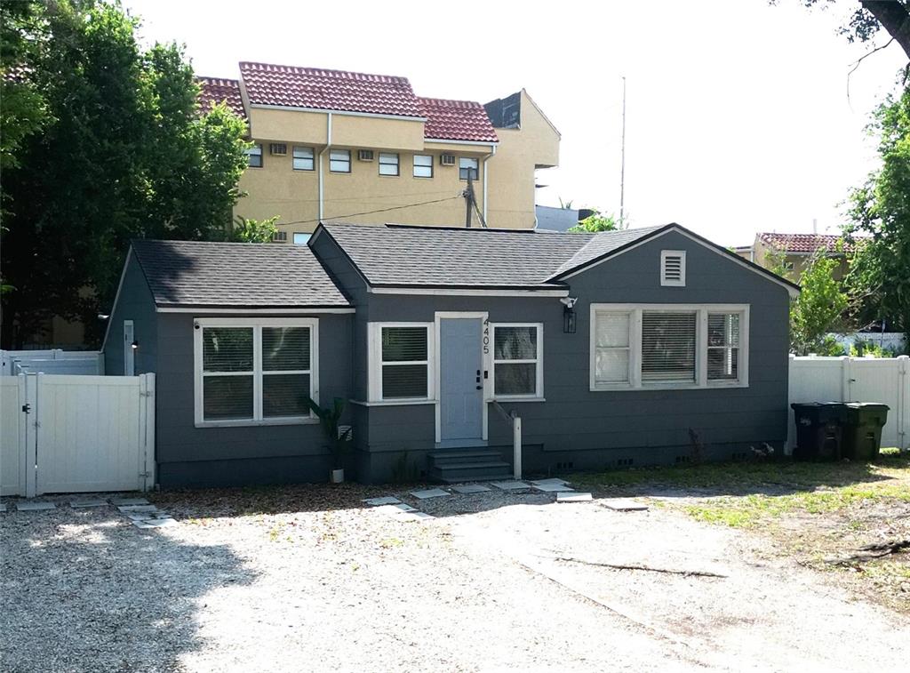 A gray, single-story house with a gravel driveway and a white fence — 4405 N TAMPANIA AVENUE, TAMPA, FL