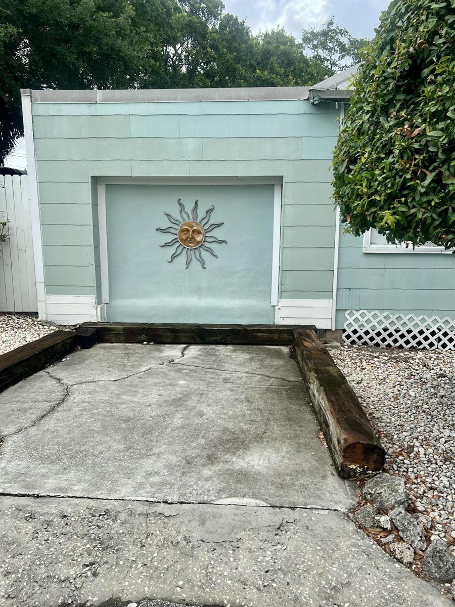 A light green exterior wall features a decorative sun ornament above a concrete parking pad — 208 Avenue E, Fort Pierce FL 34950, FORT PIERCE, FL