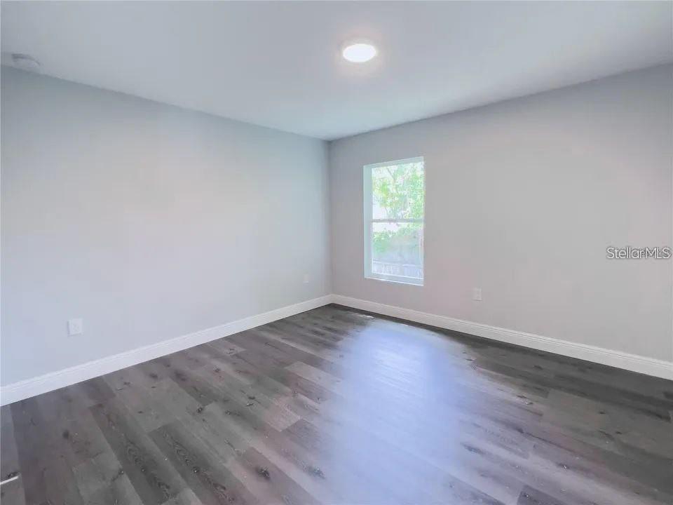 An empty bedroom features light gray walls, white trim, and dark wood-look flooring — 13435 KAPLAN TERRACE, PORT CHARLOTTE, FL