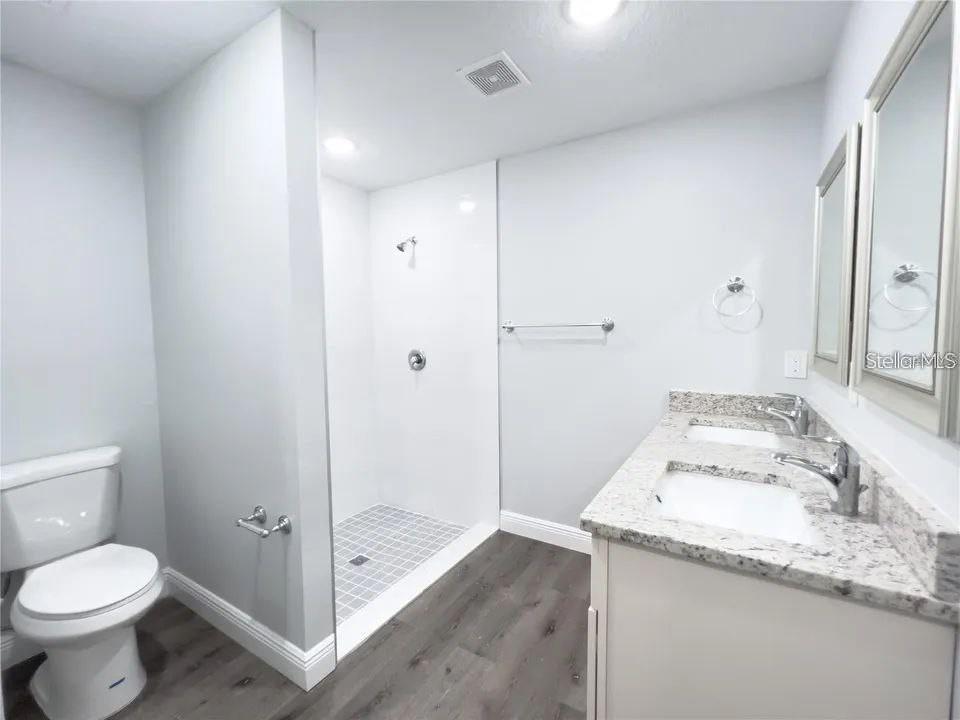 A bathroom features a double vanity with a granite countertop, a walk-in shower, and toilet — 13435 KAPLAN TERRACE, PORT CHARLOTTE, FL