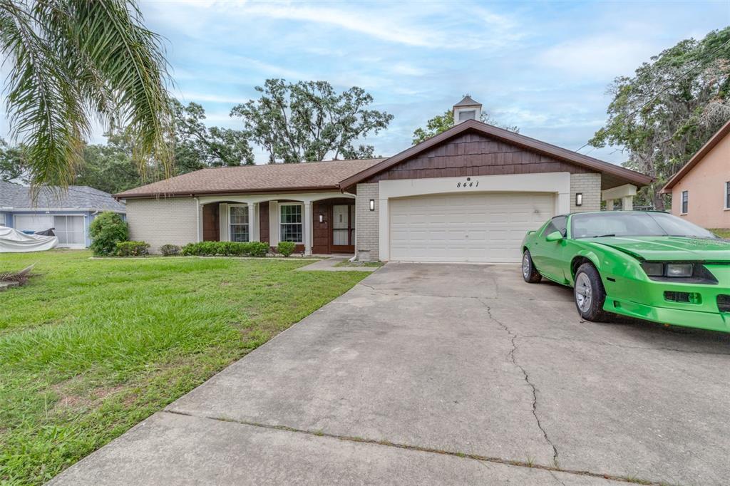A single-story house with a brick facade, a two-car garage, and a bright green car — 8441 BRAGANZA STREET, SPRING HILL, FL