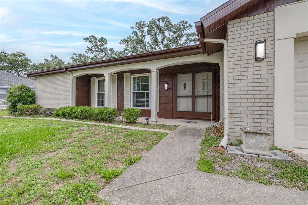 A single-story house with a brick facade, a covered entryway, and a concrete walkway — 8441 BRAGANZA STREET, SPRING HILL, FL