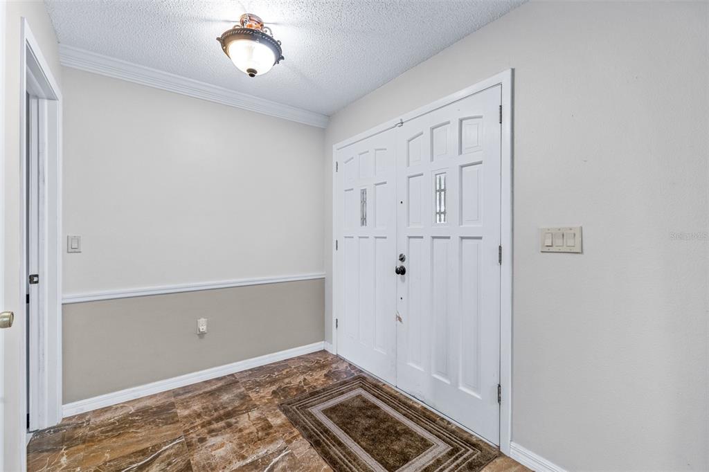 A foyer features a double front door, marble-look tile flooring, and a ceiling light fixture — 8441 BRAGANZA STREET, SPRING HILL, FL